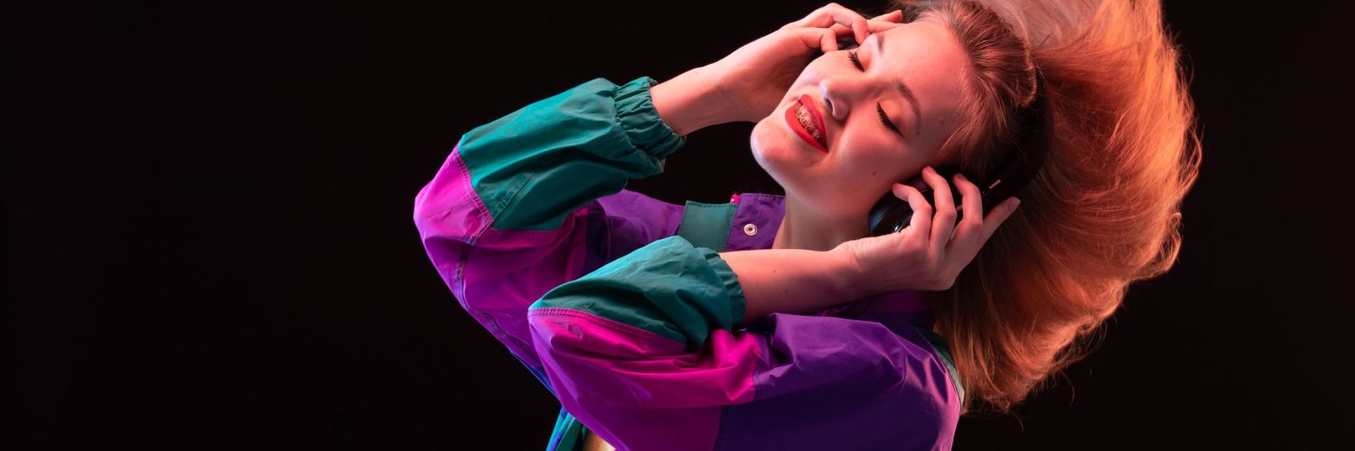 front-view-modern-young-lady-colorful-coat-orange-t-shirt-with-black-earphones-posing-listening-music-black-background-dance-modern-fashion
