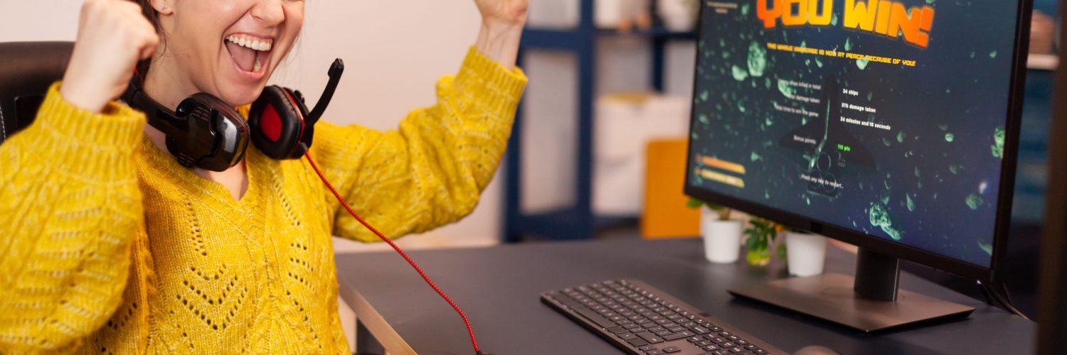 Joyful player celebrates victory winning space shooter online video game on powerful personal computer. Online streaming cyber performing during gaming tournament using technology network wireless.